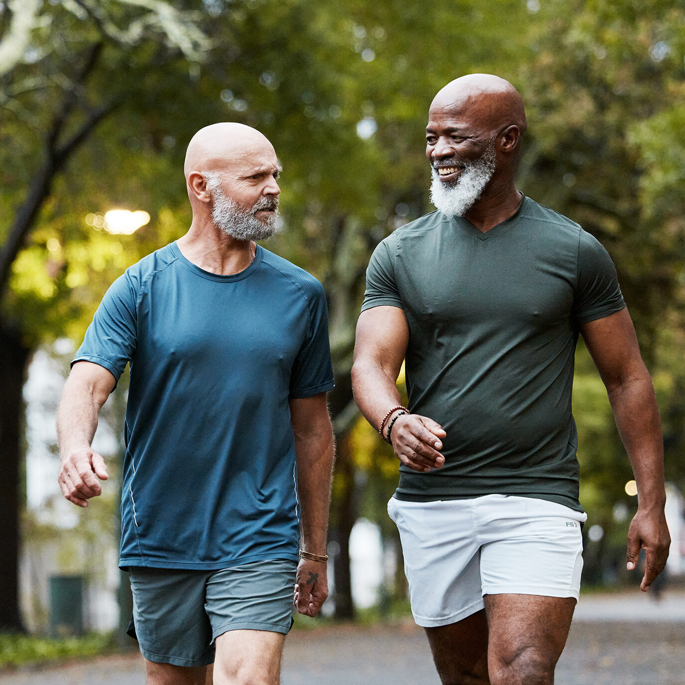 Fitness, exercise and men walking together at community park while talking and doing cardio training outdoor in nature. Diversity, friends and senior man and accountability partner on a wellness walk.