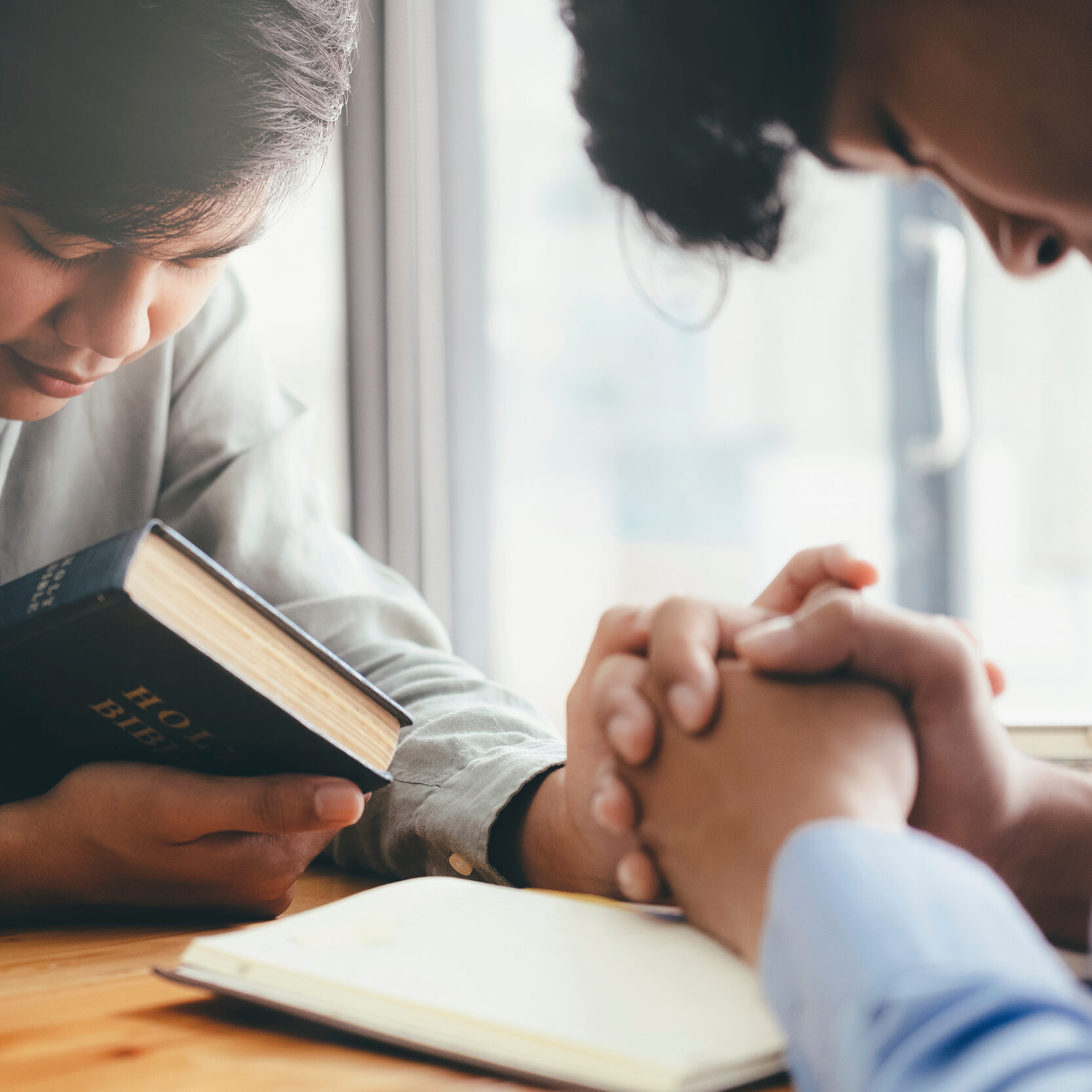 Two christian people are praying together over holy bible.